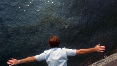 a man standing on a ledge with his arms outstretched