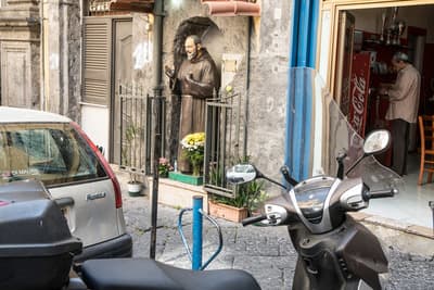 a scooter parked in front of a building with a statue of a man