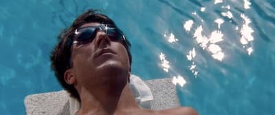a man laying on a towel in a swimming pool