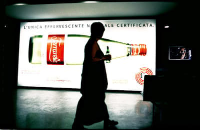 a man walking past a coca cola advertisement