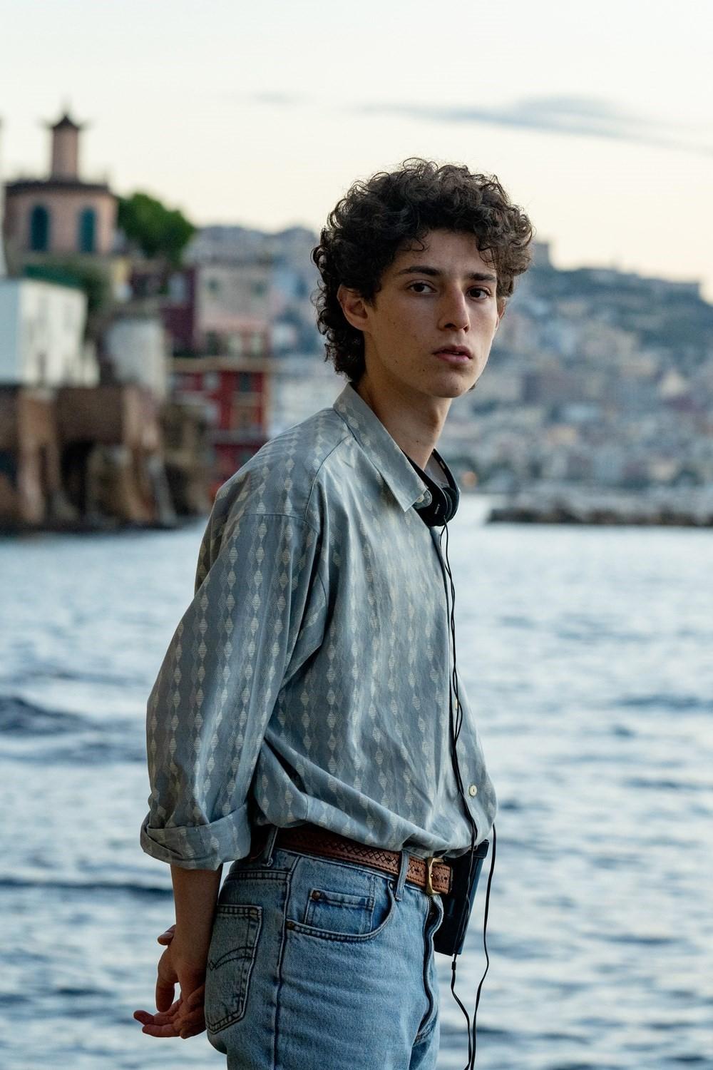 a young man standing next to a body of water