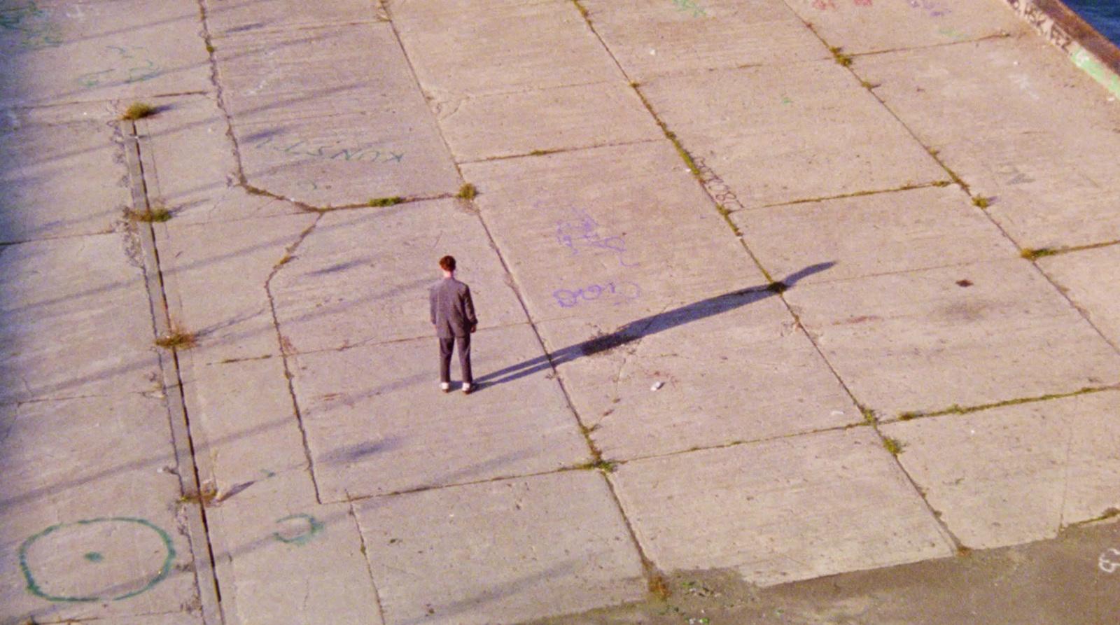 a man standing on a sidewalk next to a body of water
