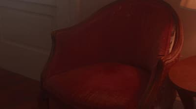a red chair next to a table with a lamp on it