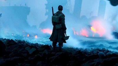 a man with a gun standing on a rocky beach