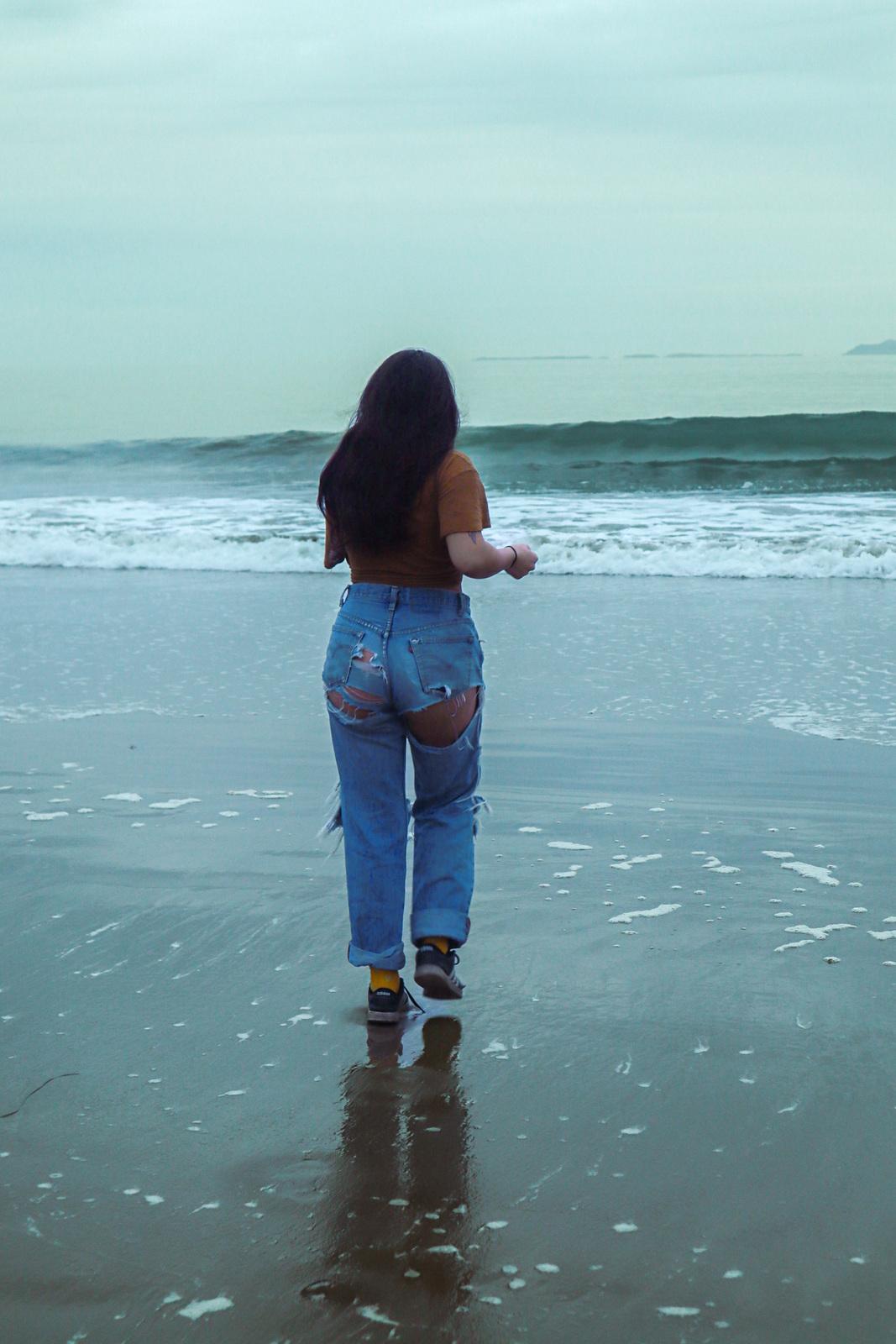 a woman standing on top of a beach next to the ocean