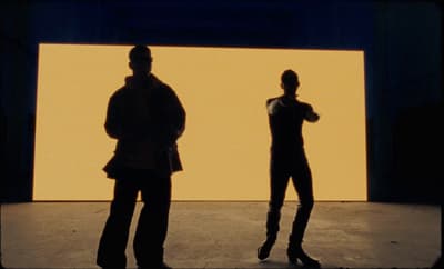 two people standing in front of a yellow wall