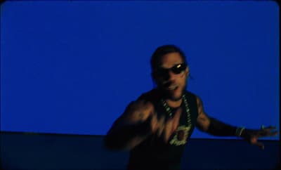 a man wearing sunglasses and a green necklace