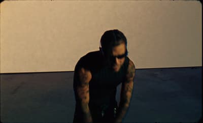 a man with a tattoo on his arm holding a skateboard