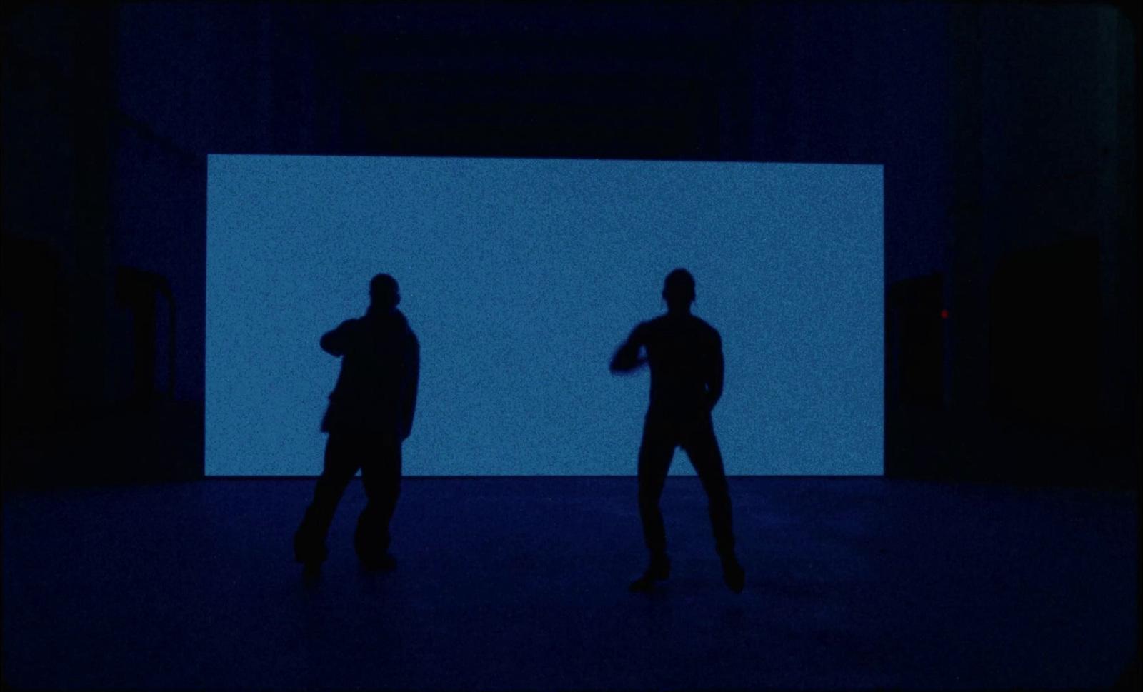 two people standing in front of a blue screen