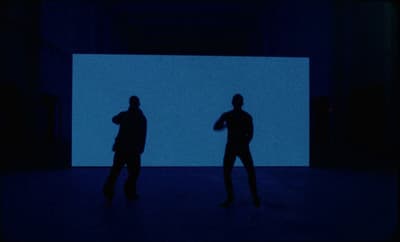 two people standing in front of a blue screen