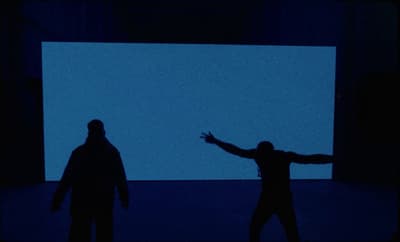 two people standing in front of a large screen