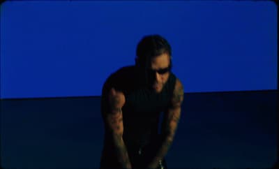 a man with long hair and tattoos holding a skateboard