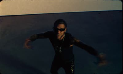 a man in a black shirt and sunglasses on a skateboard