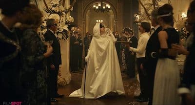 a woman in a white gown and veil standing in front of a group of people