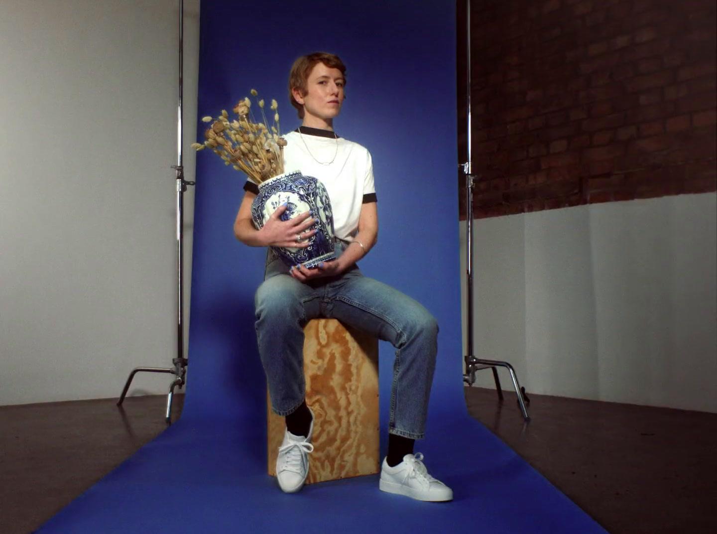 a young man sitting on a skateboard holding a bouquet of flowers