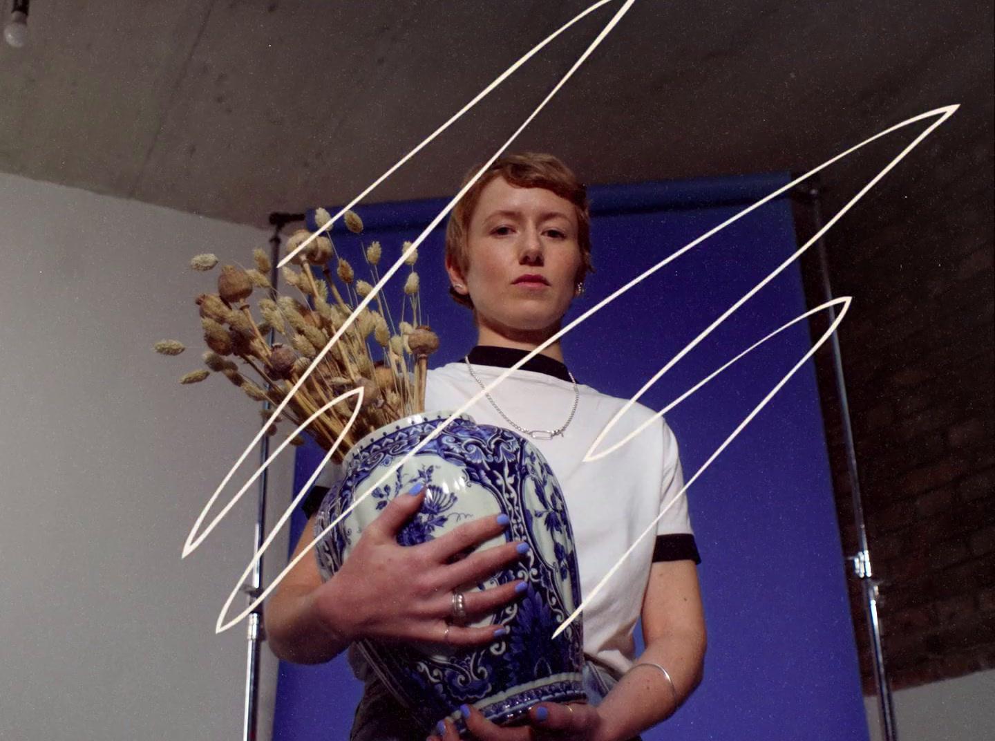 a man holding a vase with a bunch of branches in it
