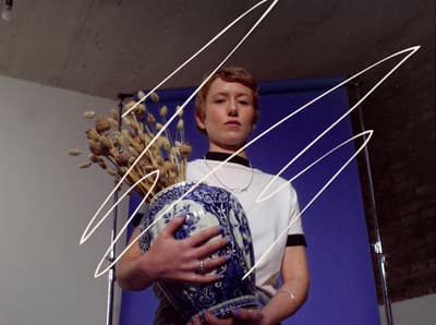 a man holding a vase with a bunch of branches in it