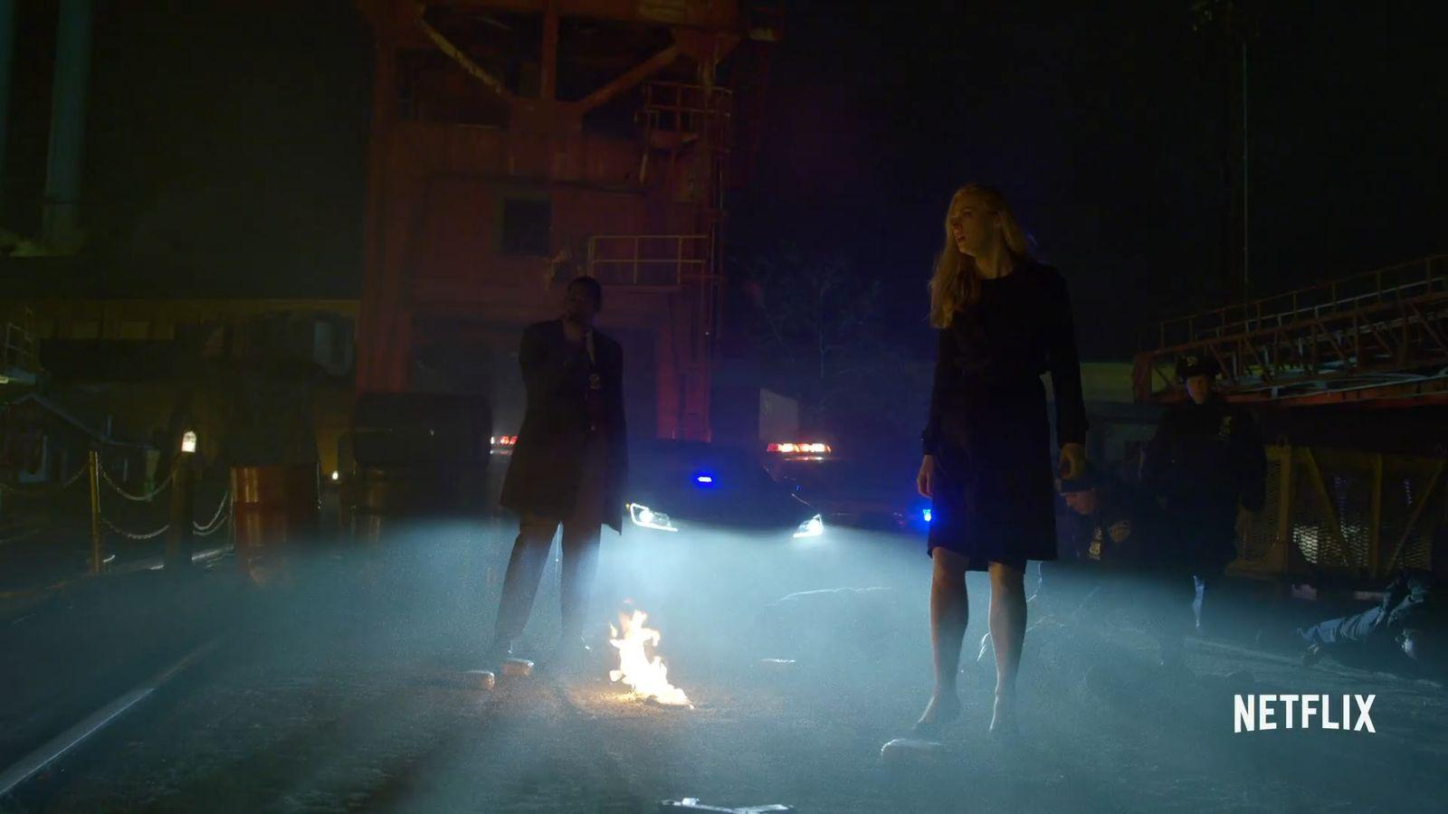 a man and a woman standing next to a fire