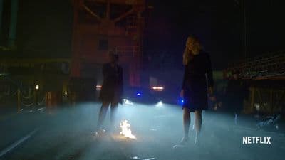 a man and a woman standing next to a fire