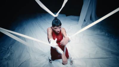 a woman in a red dress sitting on top of a bed