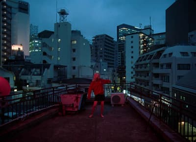 a woman in a red jacket is standing on a balcony