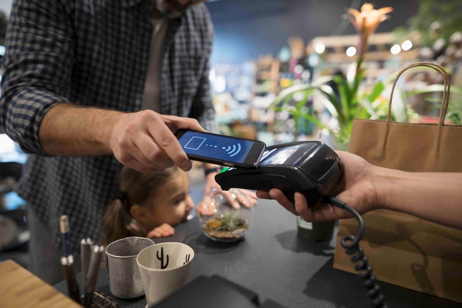 a man is paying a woman with a cell phone