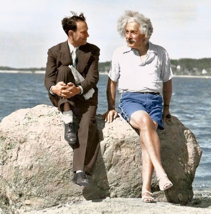 a man sitting on a rock next to another man