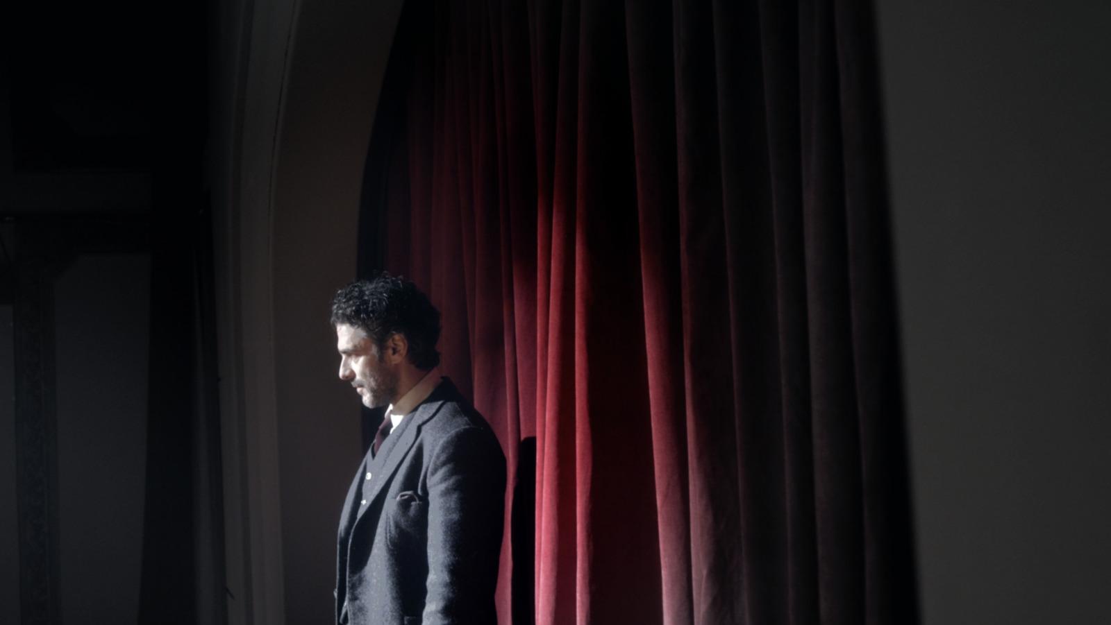 a man standing in front of a red curtain