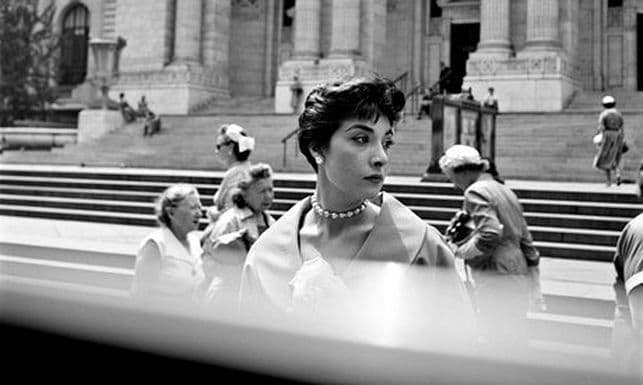 a black and white photo of a woman in front of a building