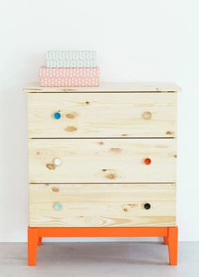 a wooden dresser with a stack of books on top of it