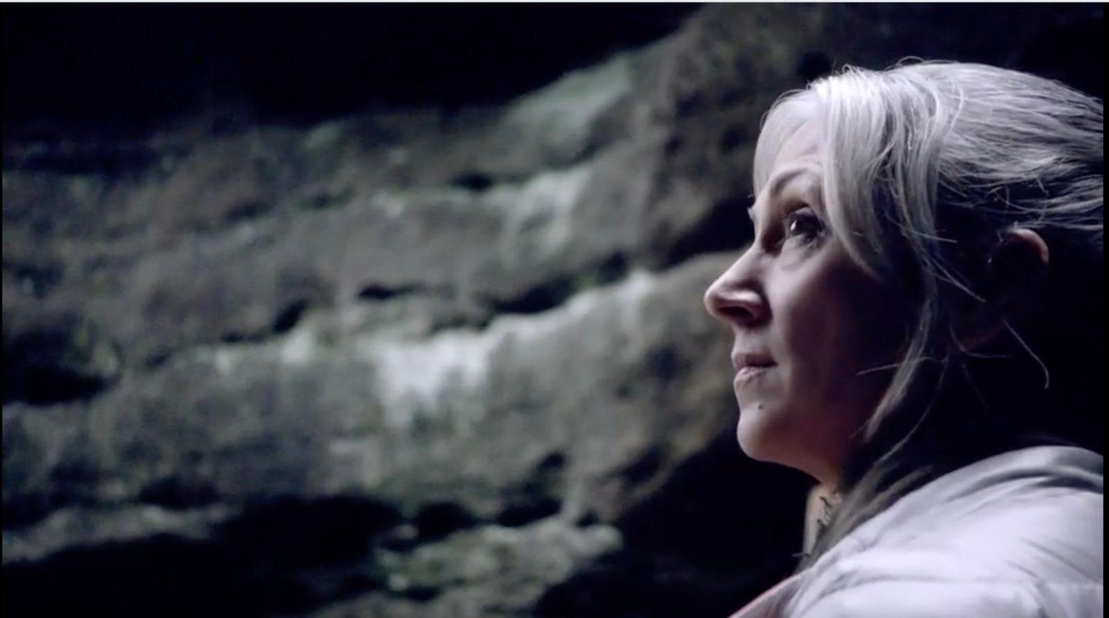 a woman standing in front of a stone wall