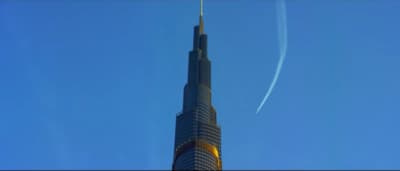 a tall building with a plane flying in the sky