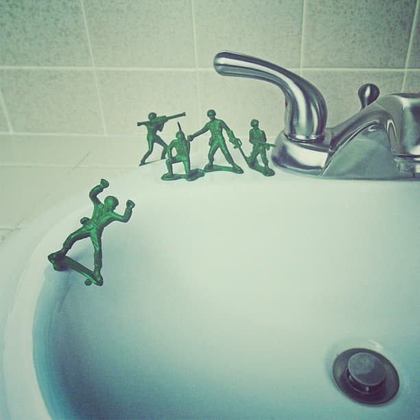 a bathroom sink filled with small green figurines