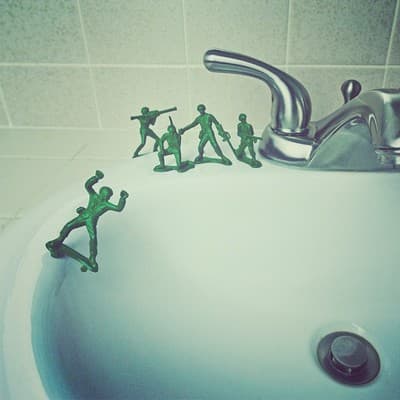 a bathroom sink filled with small green figurines