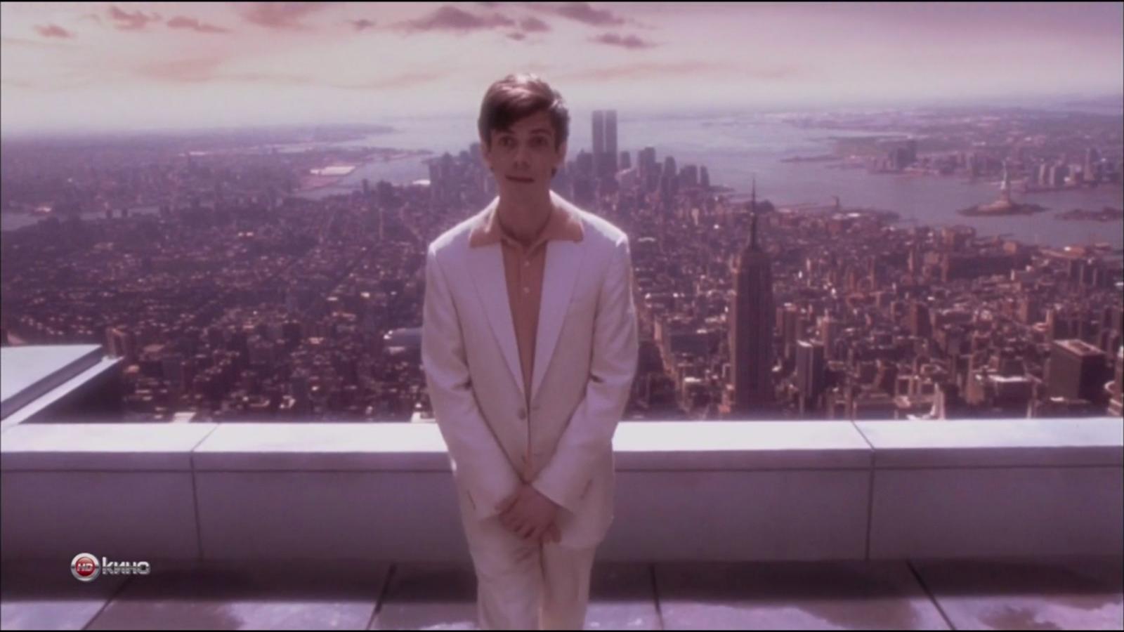 a man in a white suit standing on top of a building