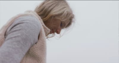 a woman in a gray sweater is looking down
