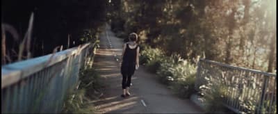 a woman walking down a path next to a forest