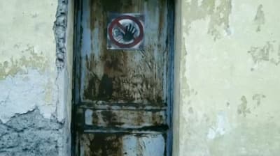 a rusted door with a no hand sign on it