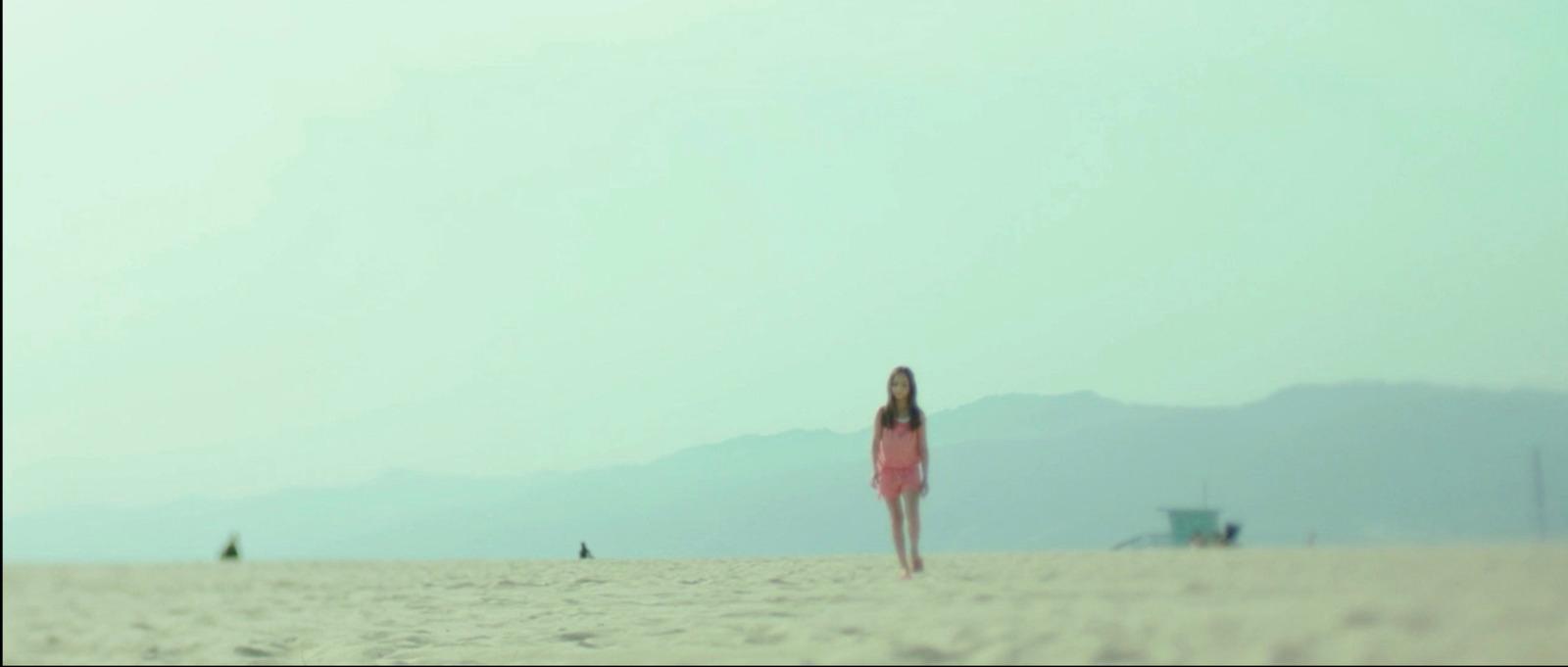 a woman in a pink dress standing on a beach