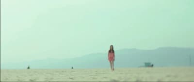a woman in a pink dress standing on a beach