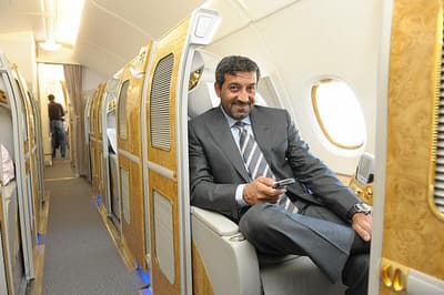 a man in a suit and tie sitting on an airplane