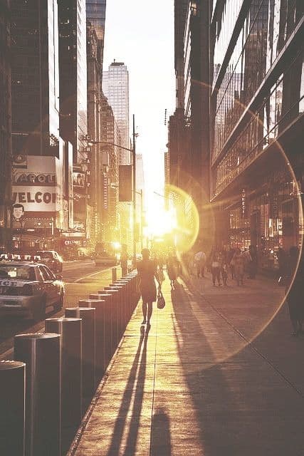 a person walking down a sidewalk next to tall buildings