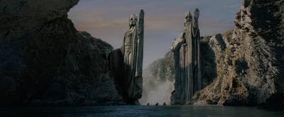 a group of tall rocks sitting next to a body of water