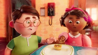 a couple of kids standing in front of a cake