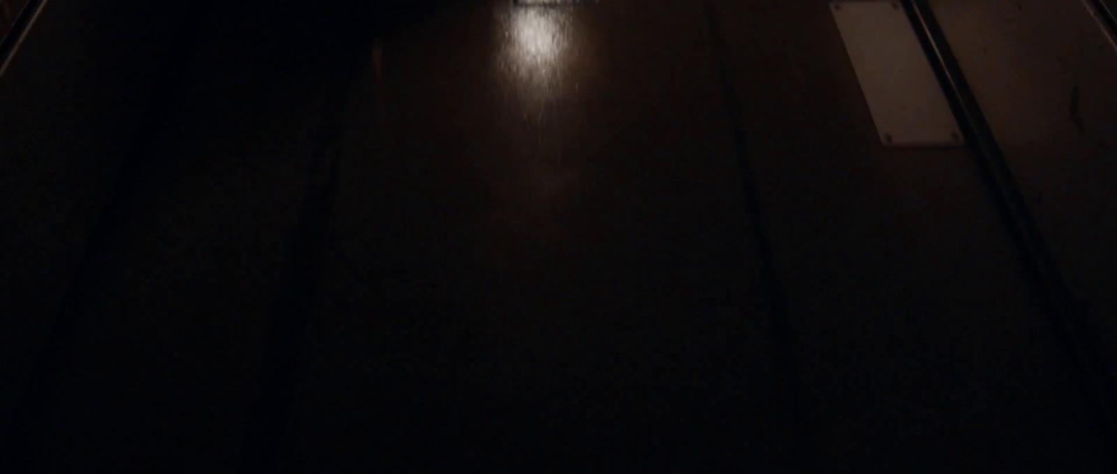 a dark hallway with a clock on the wall