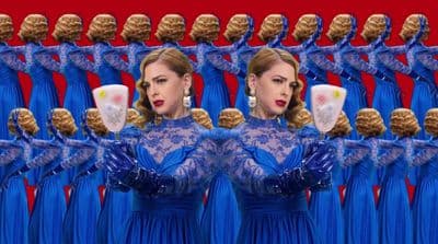 a woman in a blue dress holding a cup in front of a mirror