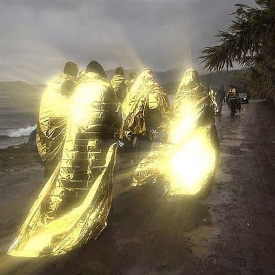 a group of people walking down a road next to the ocean