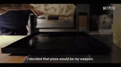 a person putting a piece of pizza into an oven