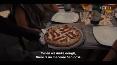 a person cutting a pizza with a knife and fork