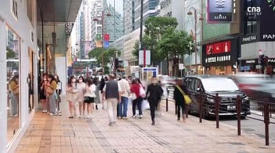 a group of people walking down a street next to tall buildings